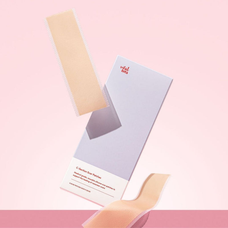 Two beige adhesive patches in a styled setting with its packaging on a pink background