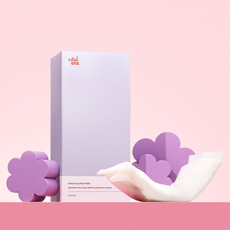 A box of instant ice padsicles with purple flower-shaped props styled around it, on a pink background