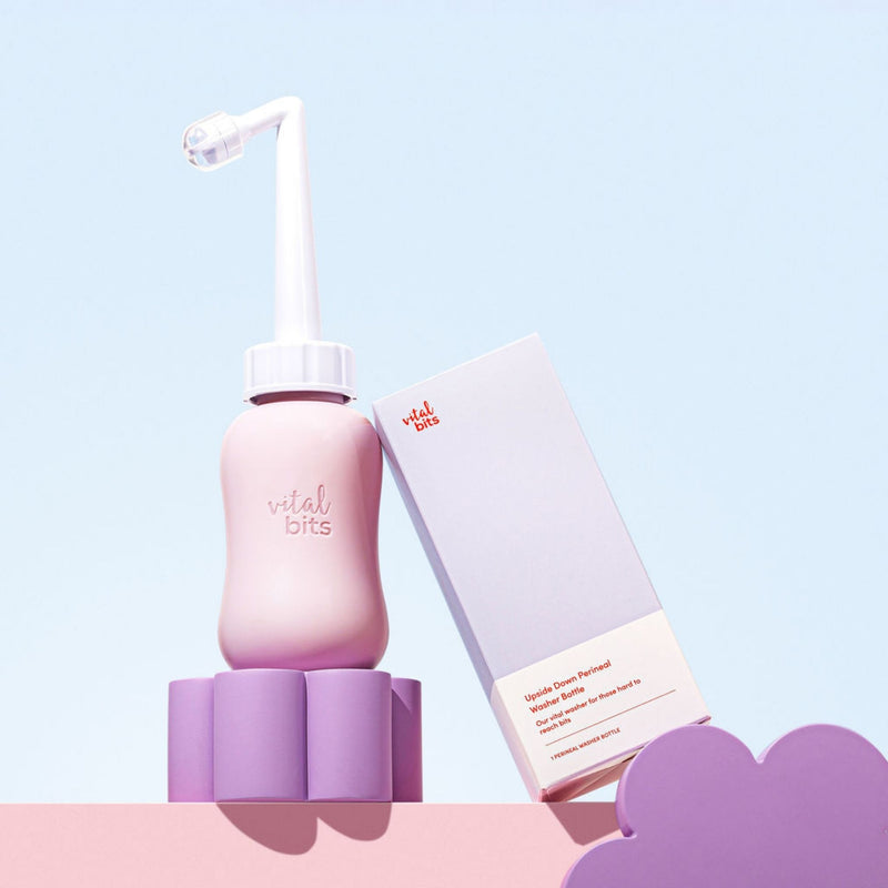 A Vital Bits peri bottle propped up next to it's packaging on a light blue background